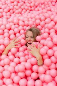 blonde haired woman lying on pink round balls