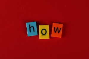 Colorful letter tiles spelling 'How' on a vibrant red background, ideal for educational content.