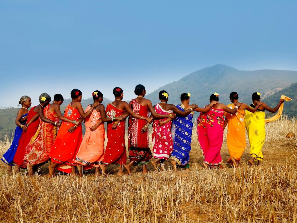 A vibrant display of cultural celebration with tribal women dancing in Araku Valley, India.