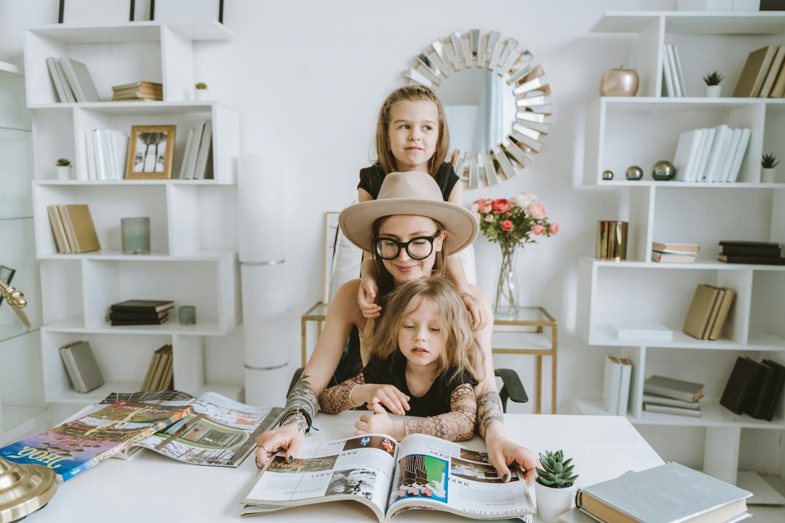 A mother and her two daughters enjoy reading a magazine together in a cozy home setting.