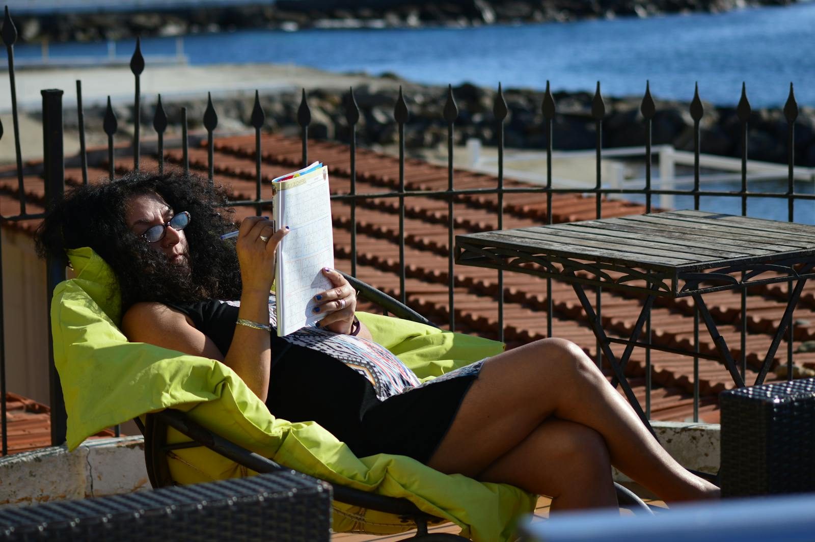 Woman lounging on a rooftop, enjoying a sunny day by the sea.