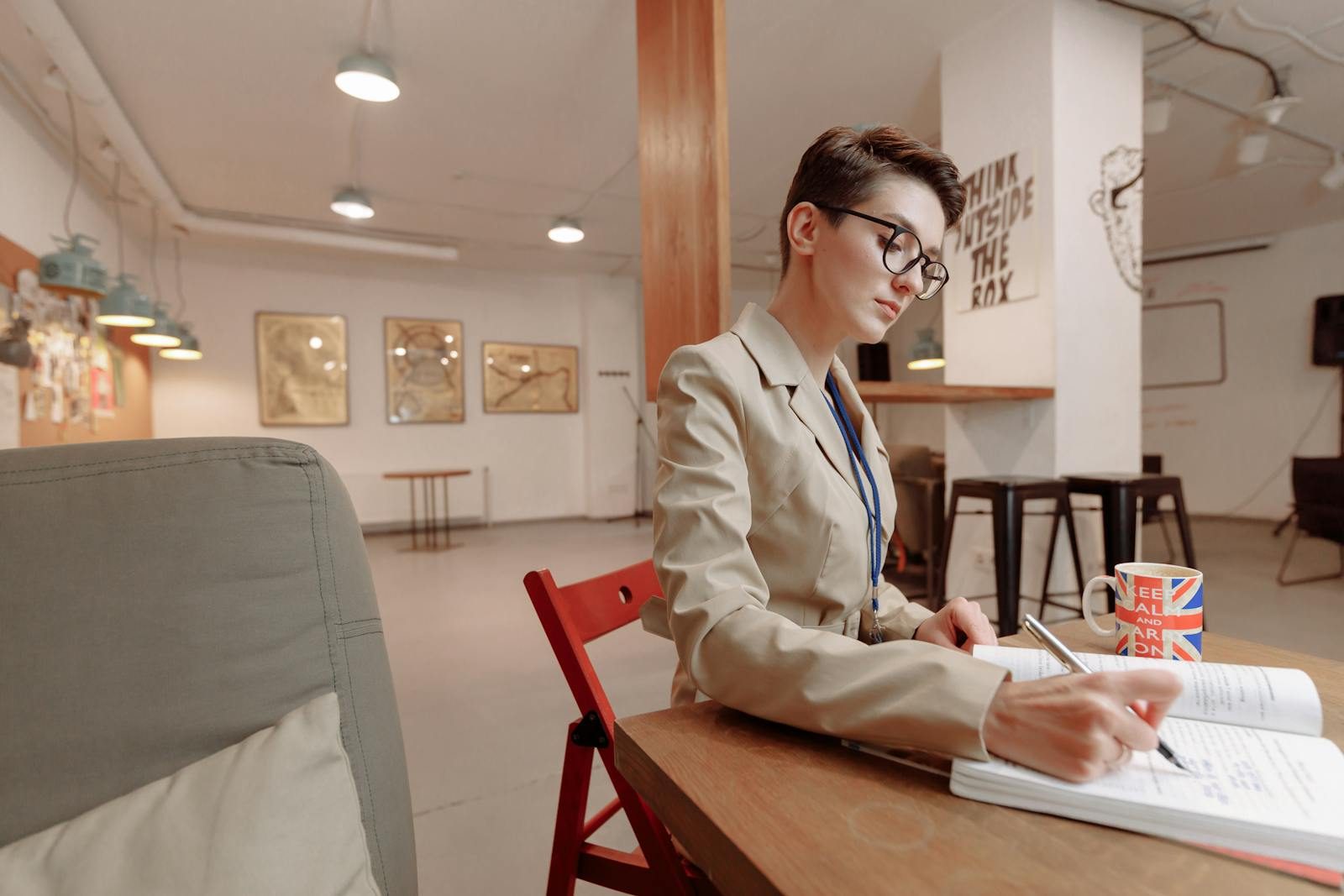 Business professional woman writing in a notebook at a modern indoor workspace.