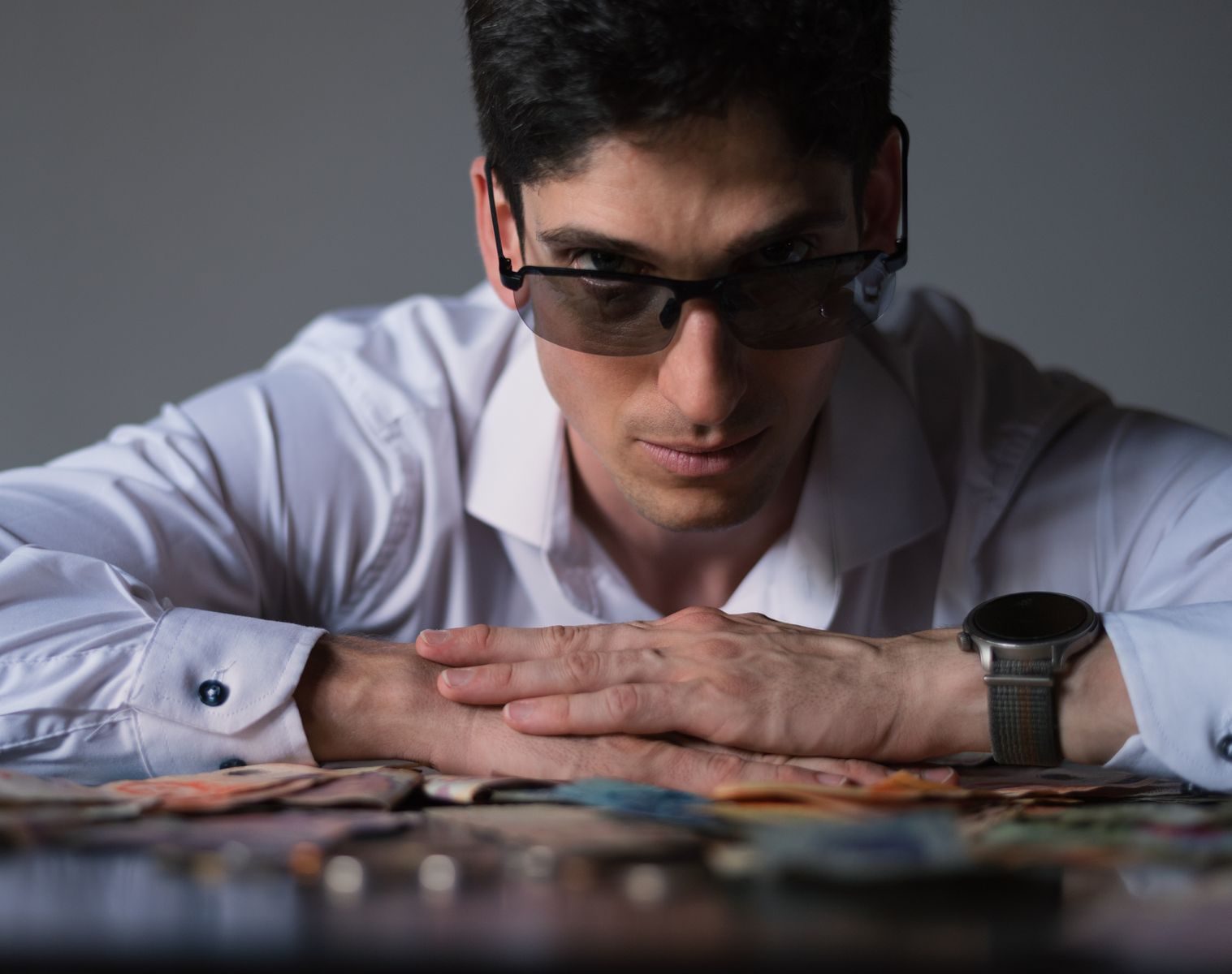 Man in sunglasses with diverse currency, exuding confidence and wealth