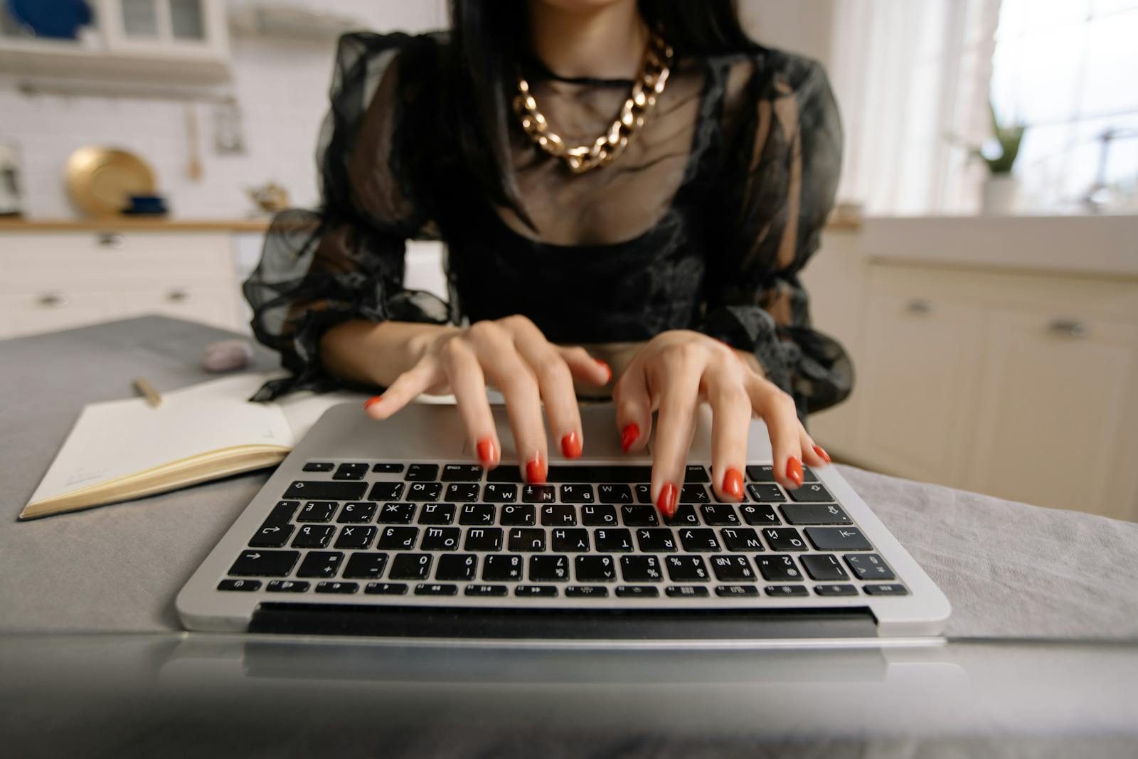 Close-up of woman typing on a laptop in a home setting, ideal for remote work themes.