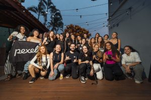 A diverse group of photographers pose outdoors at a photography meetup, showcasing their cameras.