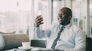 Smiling businessman on video call in a café, enjoying coffee.