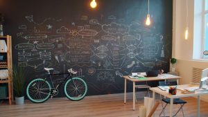 Modern office with creative chalkboard wall and bicycle, ideal for brainstorming and planning.