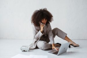 Professional woman multitasking with laptop and telephone in a minimalist office setting.