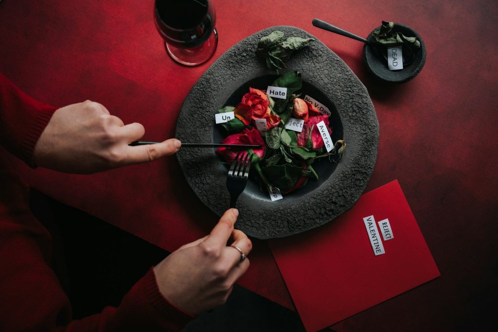 Person cutting flowers with notes on a red table