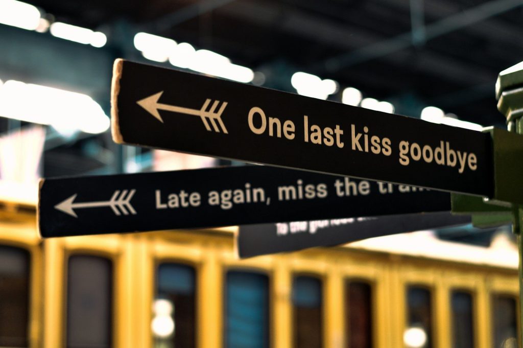 a street sign pointing in opposite directions at a train station