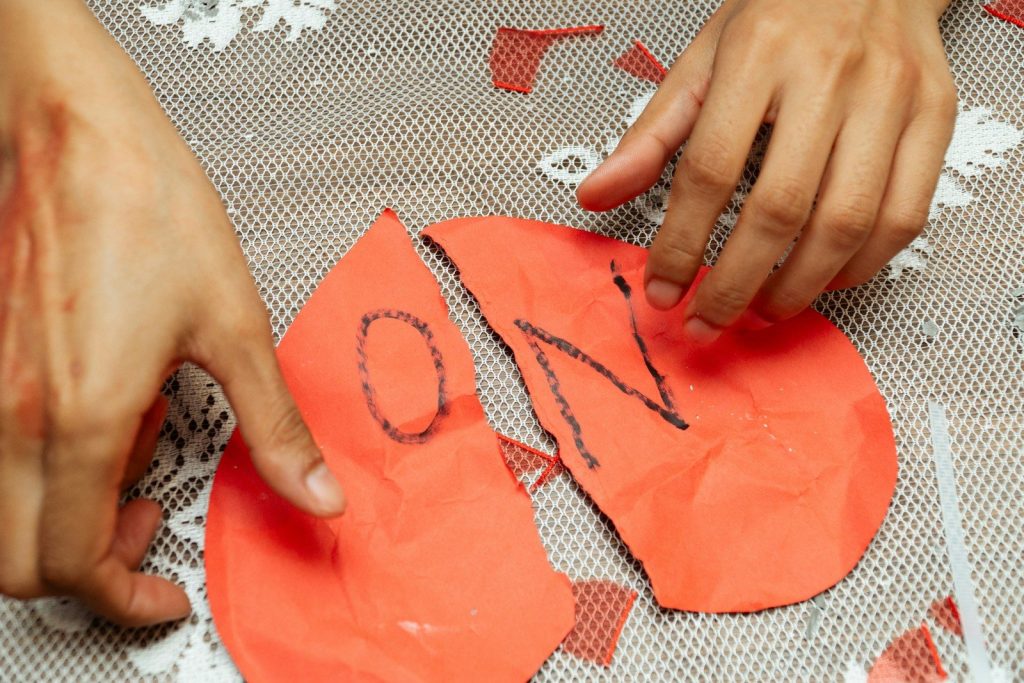 Hands arranging pieces of a broken red heart